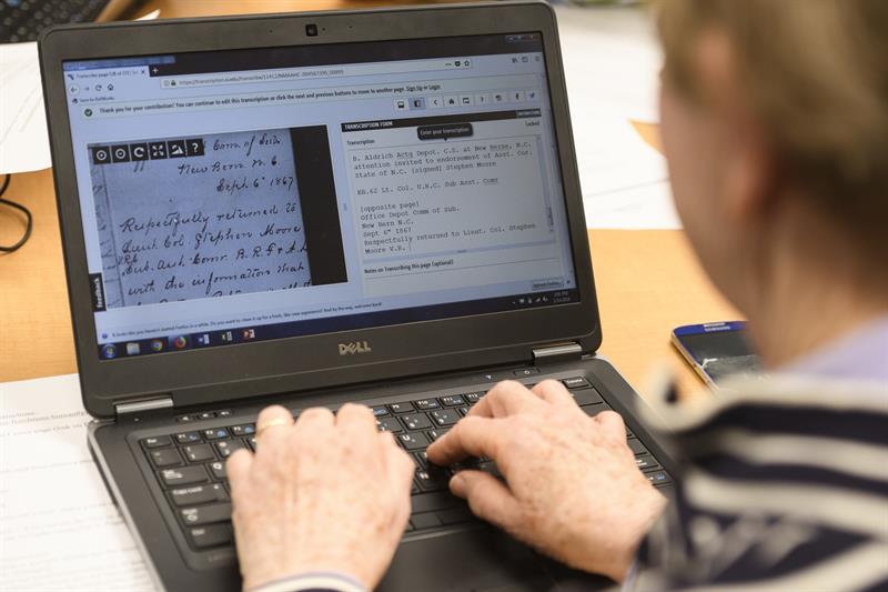 A volunteer transcribes on a laptop