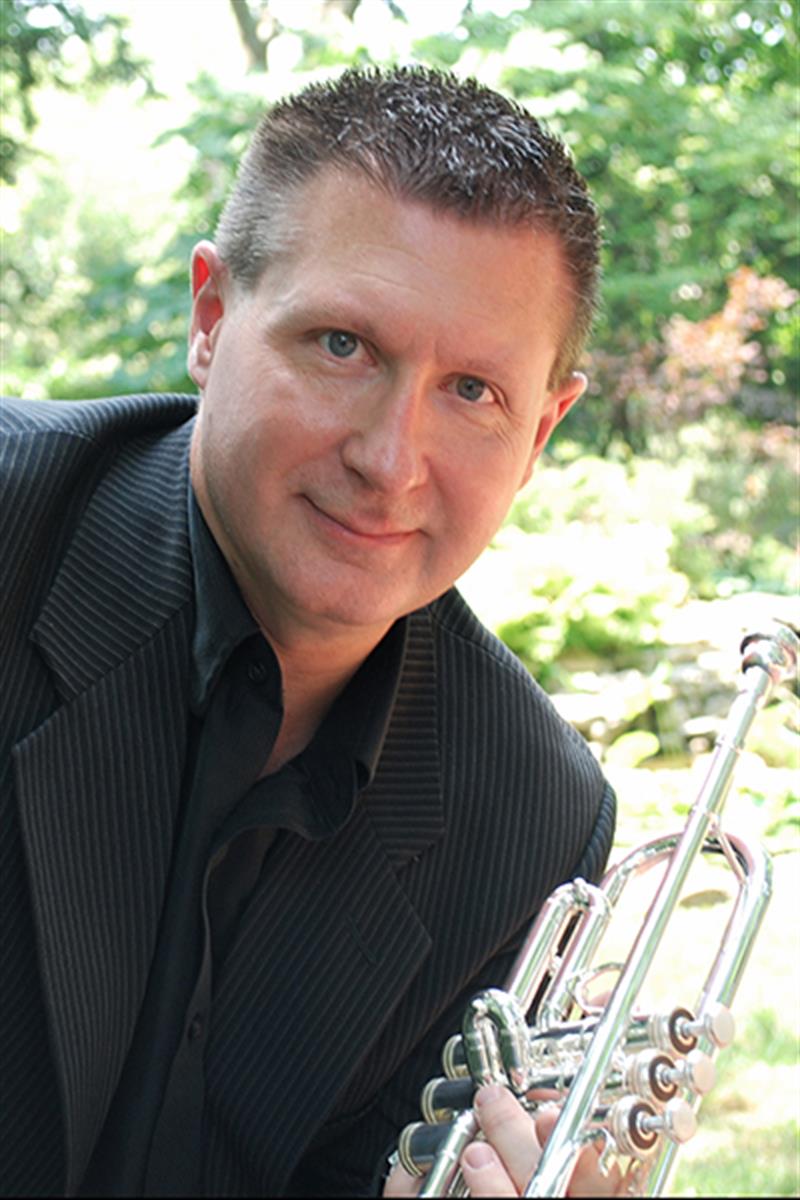 Headshot of Professor of Trumpet and UD School of Music Interim Director Mark Clodfelter, seen here holding his trumpet