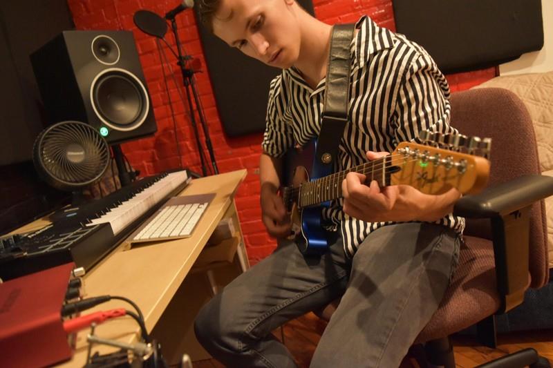 Student plays guitar in studio