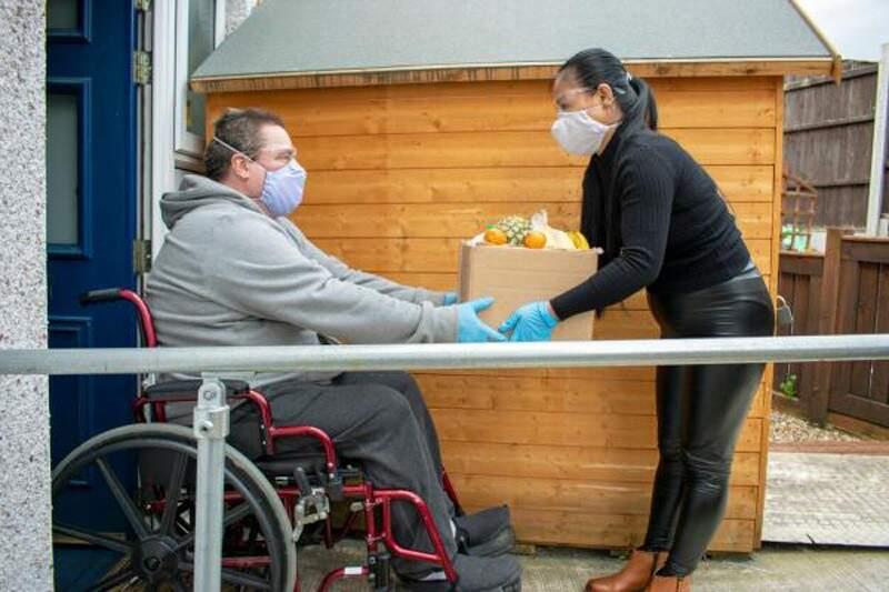 Box of food being handed to individual sitting in wheelchair