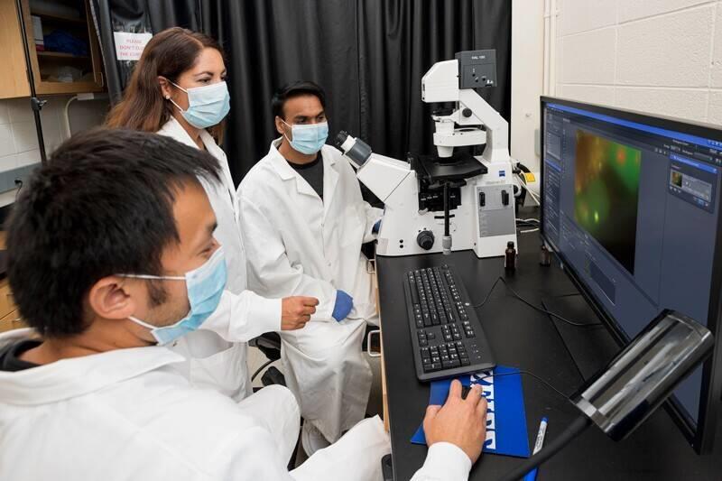 people in lab coats looking at a computer screen