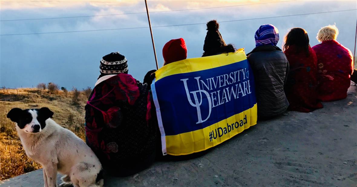 Students sitting on a ledge with UD banner