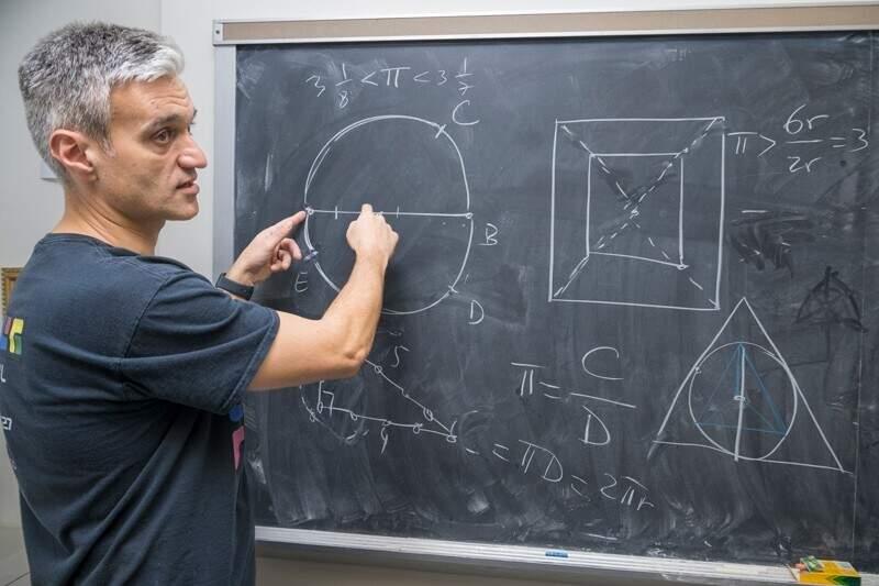 man standing at blackboard with mathmatical symbols
